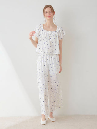 Woman wearing a Gelato Pique floral print smocked crop top and pants set with a white and blue daisy pattern, showcasing fresh fashion.