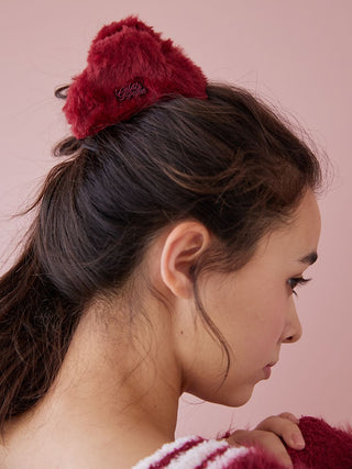 Woman wearing Gelato Pique red fur hair clip, showcasing its plush faux fur and elegant design for a warm holiday look.