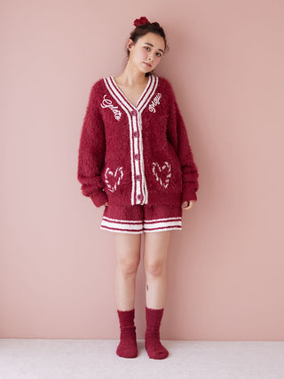 Model wearing a cozy red cardigan and shorts set, featuring embroidered hearts and lettering, with matching socks for a warm winter style.