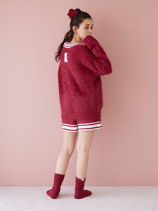 Woman wearing a cozy red fur outfit with matching socks and hair clip, facing a pink wall. The look exudes warmth and holiday style.