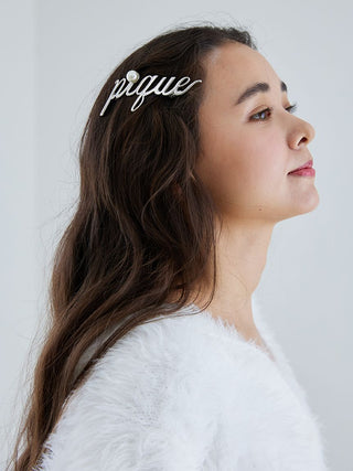 Woman wearing Metal Logo Barrette with 'Pique' script and pearl accent, showcasing minimalist design and elegance.