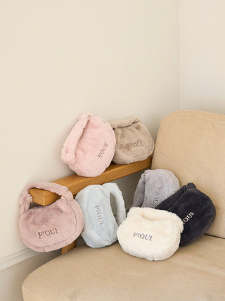 Collection of faux fur mini handbags in pastel colors on a beige sofa.