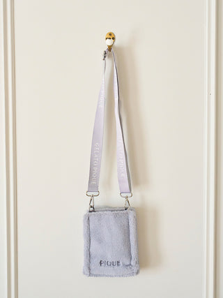 Faux fur mini sling bag with strap from Gelato Pique, hanging on a wall. Ideal for carrying small essentials with style and comfort.