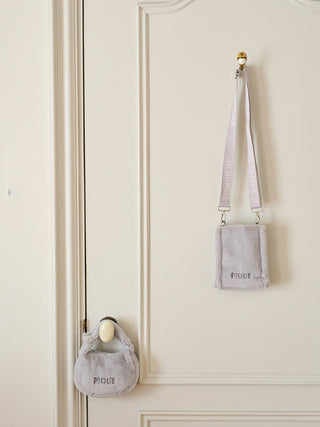 Faux Fur Mini Sling Bag from Gelato Pique hanging on a door, eco-friendly plush design in light gray with secure flap closure.