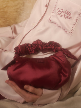 Woman holding burgundy satin handle pouch bag with scrunchie-style handle, perfect for holiday gatherings by Gelato Pique.