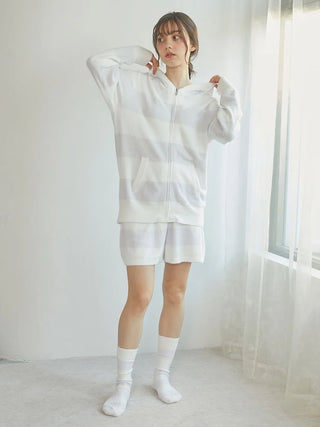 Model wearing white Gelato Pique USA loungewear set with fuzzy socks, showcasing cozy, premium sleepwear in soft natural light.