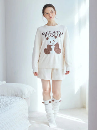 Woman wearing Gelato Pique USA off-white fuzzy socks with panda ears, premium loungewear and sleepwear, standing by a window.