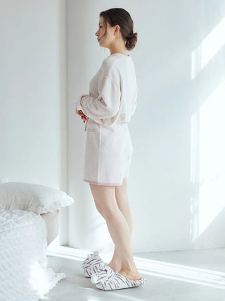 Woman wearing white Gelato Pique USA tiger slippers in a bright room, part of the premium loungewear and sleepwear collection.