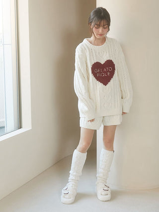 Woman wearing cozy Heart Aran long socks and matching sweater by Gelato Pique in room with natural light.