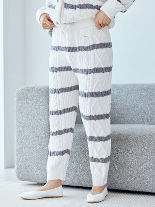 Person wearing Baby Moco Aran Border Lounge Pants with cable knit and stripe design, standing near a couch.