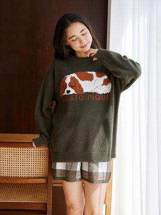 Woman wearing Gelato Pique sweater and Air Moco Checkered Lounge Shorts, standing by a chair.