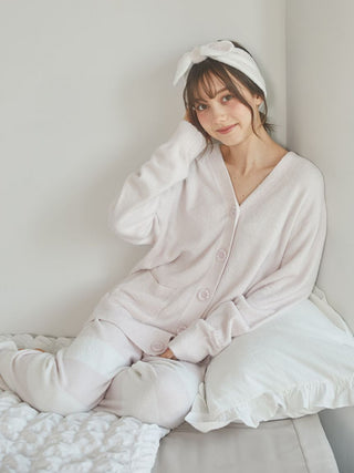 Model lounging in a pastel pink cardigan and matching pants, displaying a cozy and stylish home look.