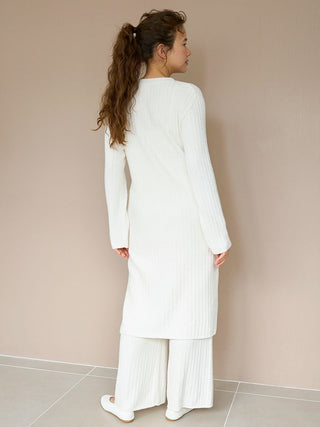 Woman wearing long white ribbed knit button-up cardigan, showcasing back view, highlighting cozy, elegant design and relaxed fit.