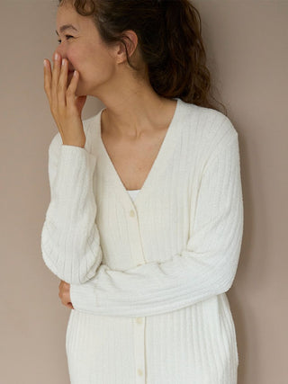 Woman wearing a long ribbed knit button-up cardigan in white, showcasing a cozy and elegant lounge style.