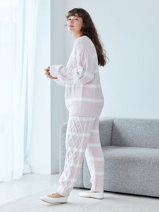 Woman wearing Baby Moco Aran Pullover Sweater, showcasing soft fabric and classic cable knit pattern with chic stripes in a cozy setting.