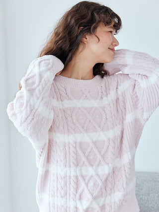 Woman wearing a pink Baby Moco Aran Pullover Sweater with cable knit pattern and horizontal stripes.