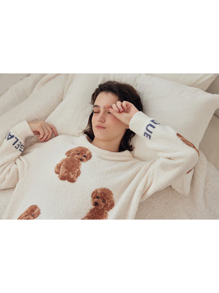 Woman wearing cozy Toy Poodle Pullover Sweater with jacquard poodle motifs, resting on a bed.