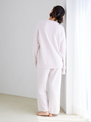 Back view of a woman wearing a cozy Powder Biscuit Jacquard Pullover Sweater and matching pants, standing by a window.