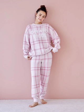 Woman wearing pink checkered pajama set by Gelato Pique against a pastel pink background, showcasing cozy loungewear fashion.