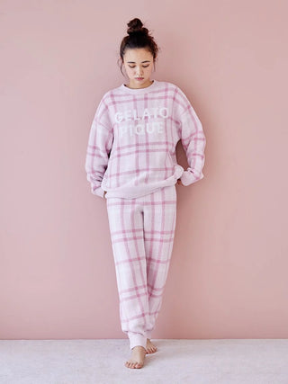 Woman wearing Gelato Pique checkered pajama set in soft pastel tones against a pink background