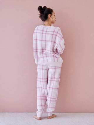 Woman wearing pastel checkered pajama set by Gelato Pique, showcasing relaxed-fit and cozy design on a soft pink background.