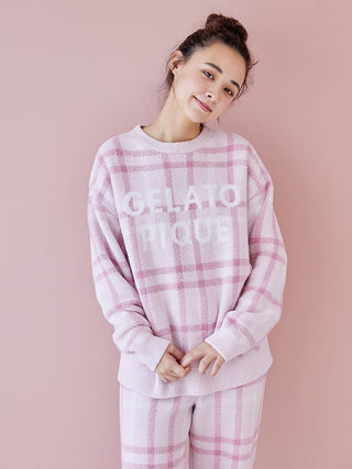 Woman wearing Gelato Pique checkered pajama set in pastel tones, standing against a pink background.