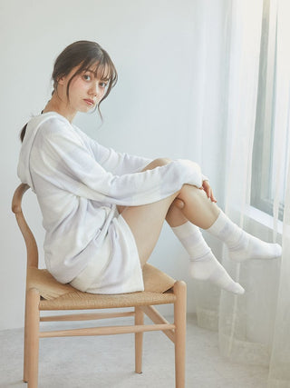 Young woman seated in a cozy white parka, showcasing style and comfort in a bright, airy room.