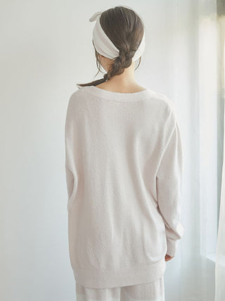 Back view of a woman wearing a soft pastel cardigan with a loose fit and long sleeves, showcasing a trendy and comfortable style.