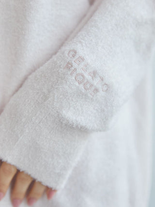 Close-up of a white cardigan sleeve with subtle 'GELATO PIQUE' embroidery.