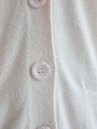 Close-up of pastel buttons on a soft cardigan, highlighting the delicate texture and branding details.