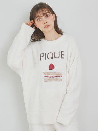 Woman wearing Cake Jacquard Pullover Sweater with cake motif and PIQUE lettering, showcasing cozy and playful loungewear style.