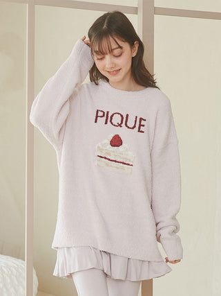 Woman wearing Cake Jacquard Pullover Sweater with cake motif and PIQUE lettering, showcasing cozy loungewear style.