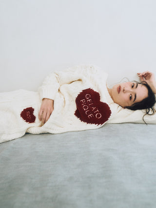 Woman wearing Heart Aran Pullover Sweater with Gelato Pique logo, featuring cozy Aran cable-knit and embroidered heart motifs.