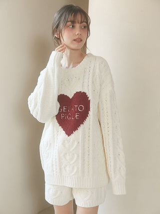 Woman wearing Heart Aran Pullover Sweater with embroidered heart and Gelato Pique logo, showcasing cozy cable-knit design.