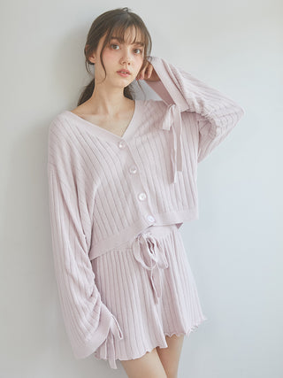 Woman wearing pink ribbed knit shorts and cardigan set with feminine merrow hemmed design, showcasing cozy spring fashion.