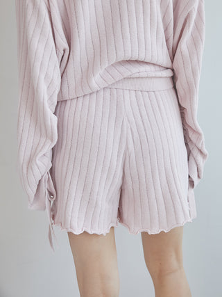 Model wearing pink ribbed knit shorts with a ruffled hem, paired with a matching sweater.