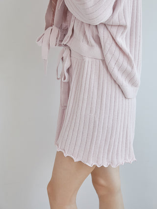 Woman wearing pink ribbed shorts with wavy hem and matching cardigan