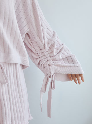 Close-up of a light ribbed cardigan sleeve with drawstring detail, showcasing its cozy texture and stylish design.