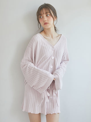 Woman wearing a light pink ribbed cardigan, showcasing casual elegance and cozy comfort, perfect for stylish loungewear.